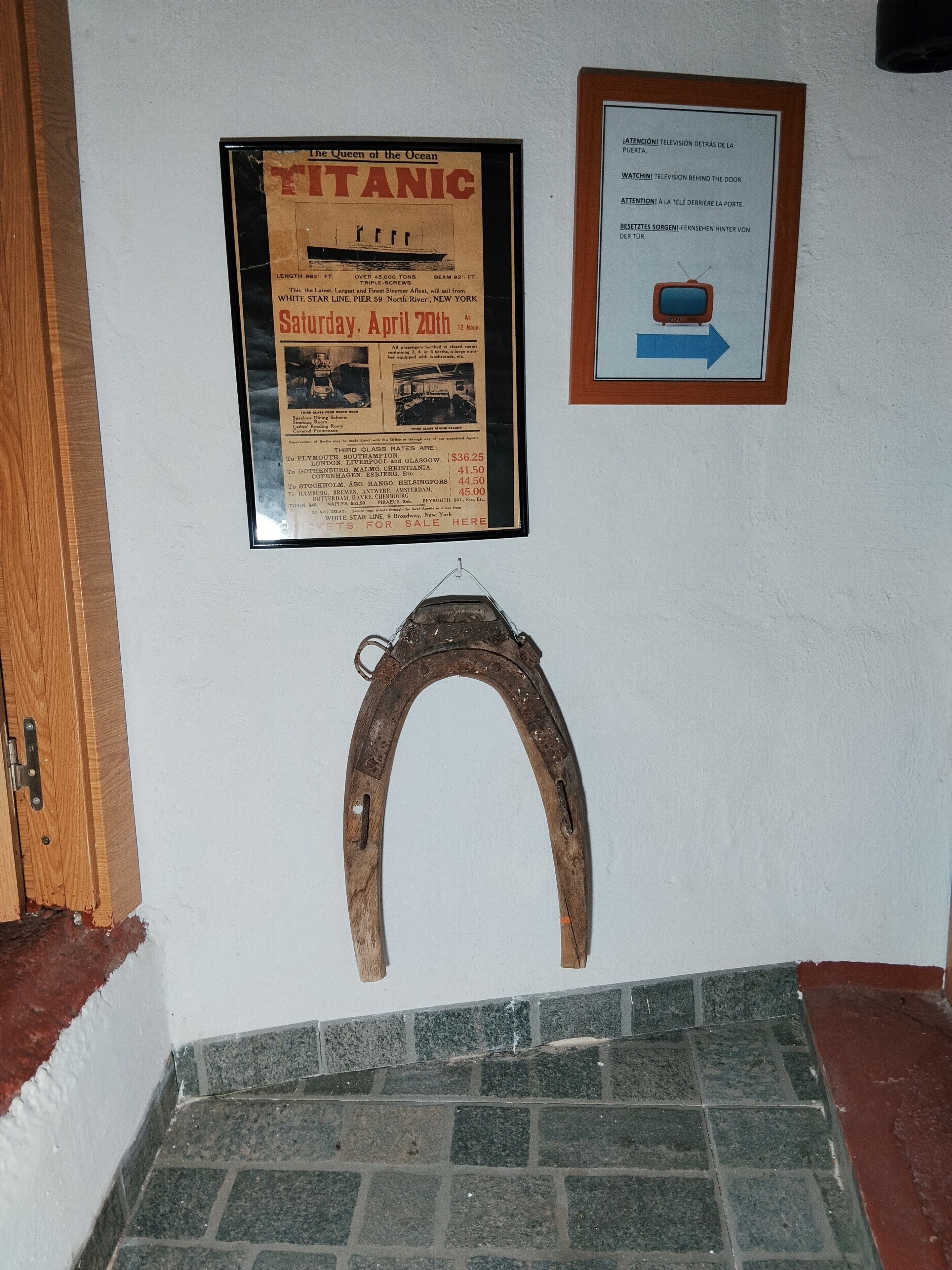 Un cartell emmarcat de la Titanica, un senyal d'instruccions de televisió emmarcat i una herradura penjada a la paret.