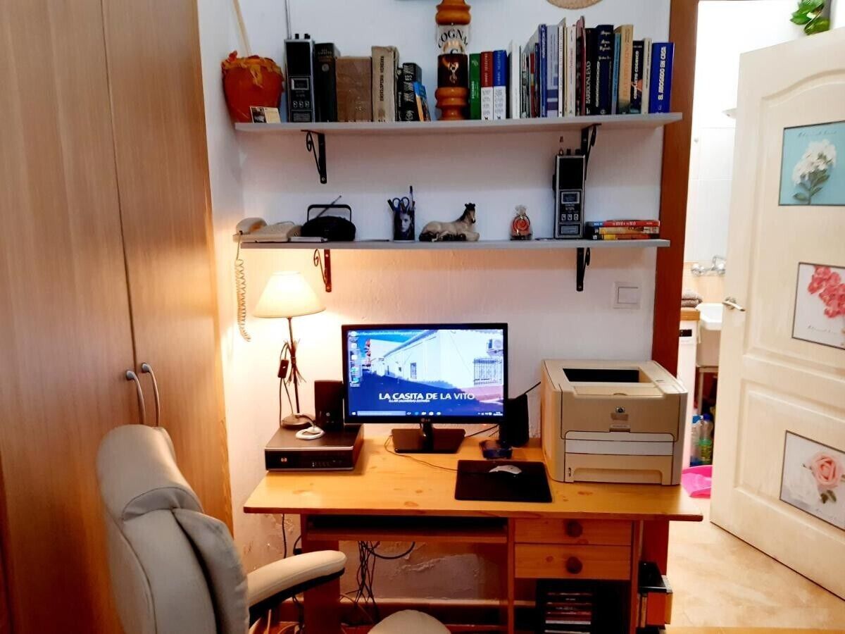 Un espacio de trabajo en casa con escritorio, computadora y estantería.