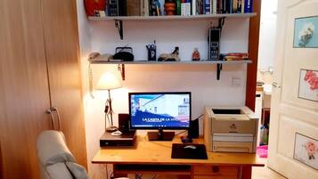 Un espacio de trabajo en casa con escritorio, computadora y estantería.