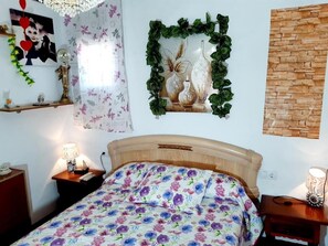 Une chambre à coucher avec un lit, des tables de chevet, une horloge murale, un tableau encadré et un mur en briques.