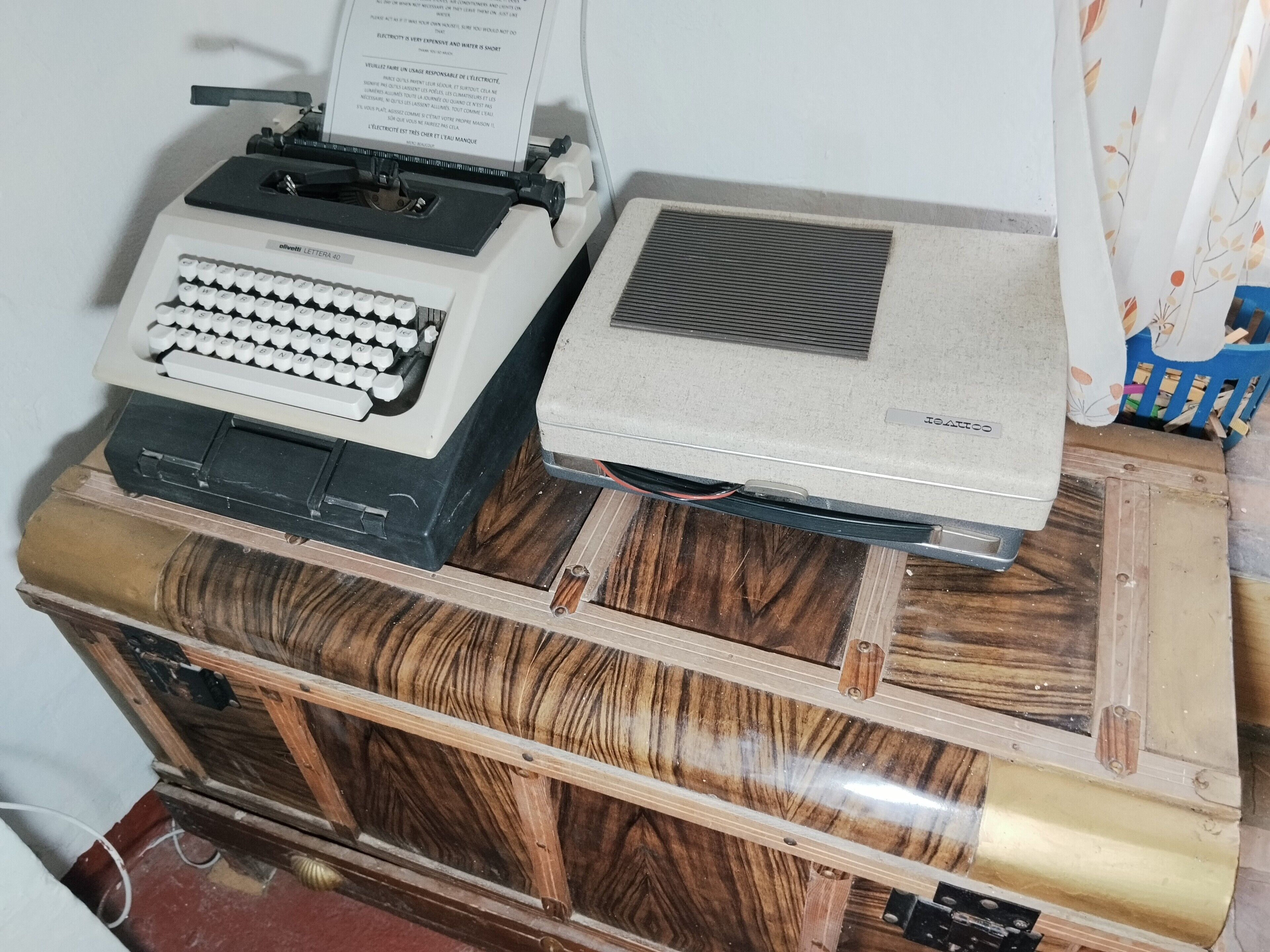 An Olivetti Lettera 2 typewriter and a vintage printer on a wooden cabinet.