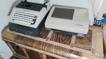 An Olivetti Lettera 2 typewriter and a vintage printer on a wooden cabinet.