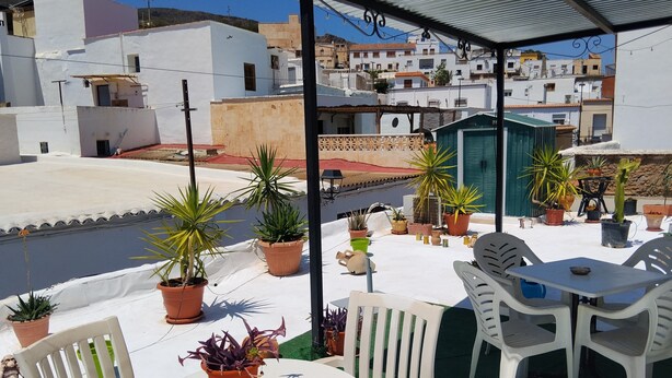 Une terrasse sur le toit, agrémentée de plantes en pot, de sièges d’extérieur et offrant une vue sur le paysage urbain.