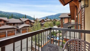 Un balcon offrant une vue sur plusieurs chalets en bois et sur un paysage montagneux en arrière-plan.