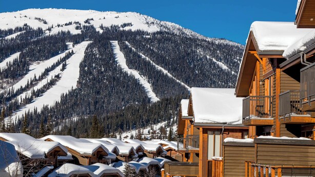 Une station de ski avec des chalets en bois et une montagne enneigée en arrière-plan.