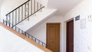 A staircase with a wooden handrail and black metal balusters, a wooden door, and a wall-mounted sign with the number '19A'. - Studio Apartment '19A Claire' with Pool, Private Garden & Wi-Fi (El Paraiso)