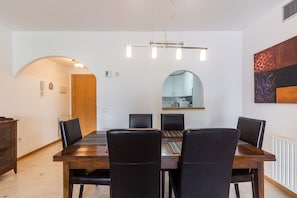 A dining area with a wooden table and black chairs, a hanging light fixture, and a large mirror on the wall. - Holiday Apartment Guadalmina Alta with Mountain View, Shared Pool & Wi-Fi (San Pedro De Alcántara)