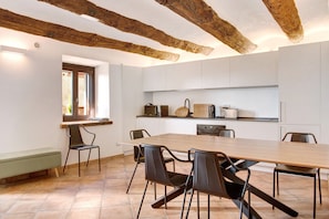 Une cuisine moderne avec des meubles blancs, une table à manger en bois et des chaises noires.