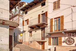 Une rue étroite bordée d’immeubles dotés de balcons, de volets en bois et d’un mur en pierre.