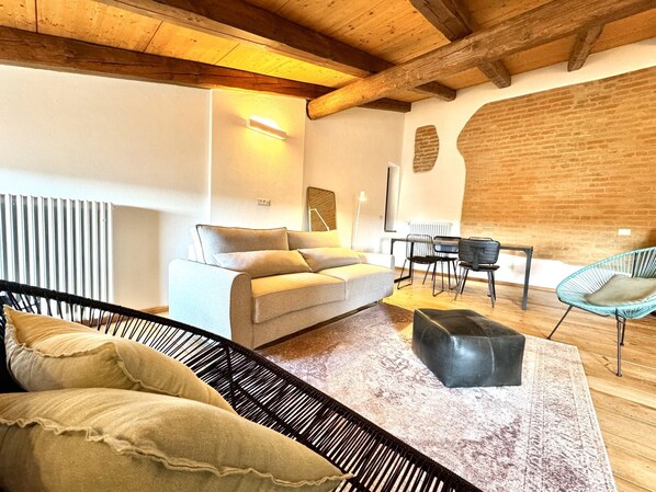 Un salon moderne comprenant un canapé, une table basse, une table à manger avec des chaises et un plafond en bois.