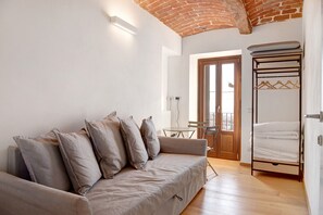 Una habitación con sofá, cama, mesa y puerta que da a un balcón exterior.