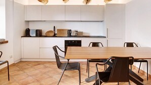 Una cocina moderna con armarios blancos, una mesa de madera y sillas negras.