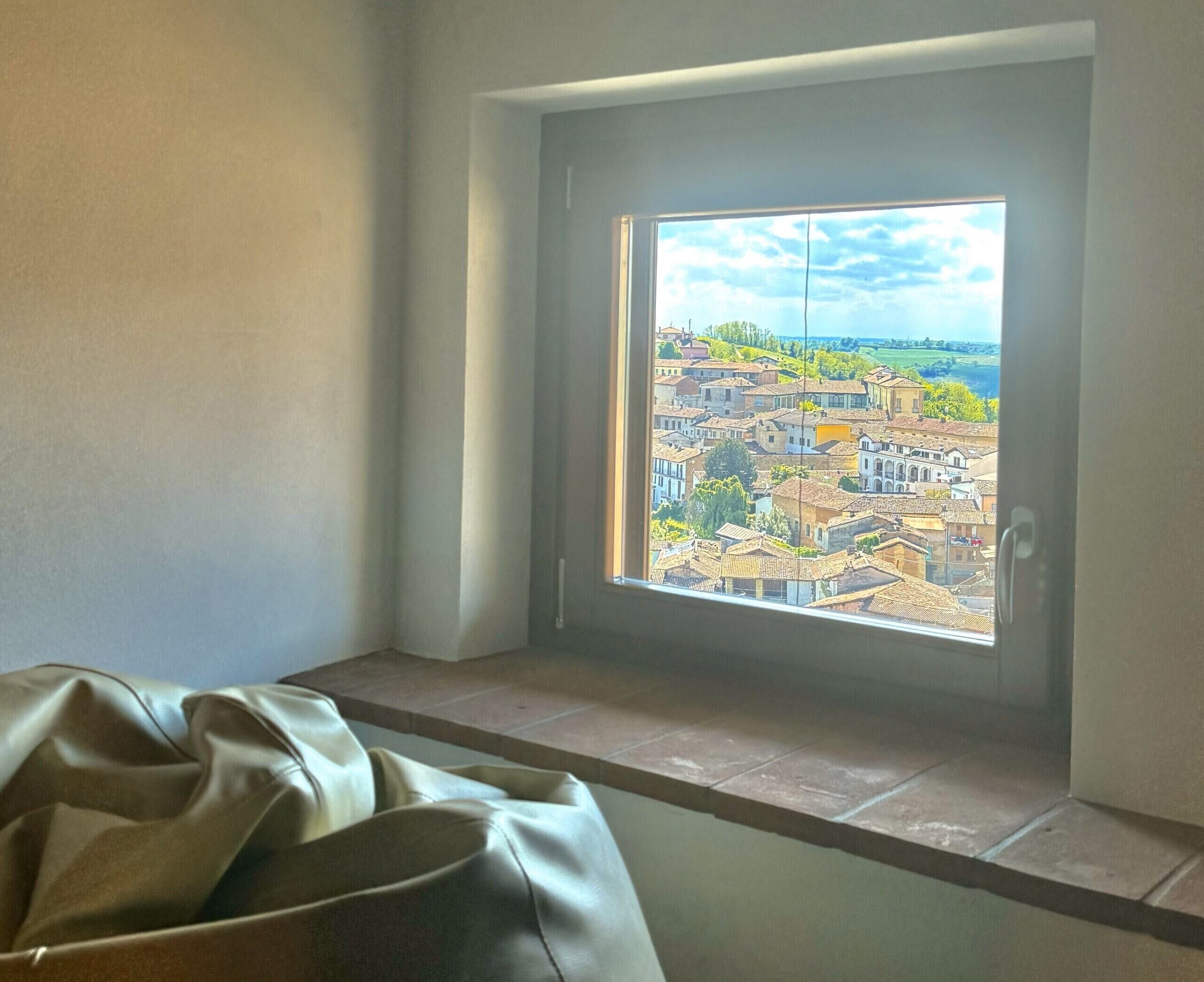 Ein Zimmer mit Blick auf eine Stadt, inklusive Fenster, einer Bank und einer Tür.