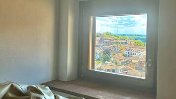 Ein Zimmer mit Blick auf eine Stadt, inklusive Fenster, einer Bank und einer Tür.