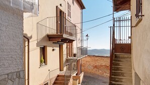 Una calle estrecha con un edificio que tiene un balcón y una escalera.