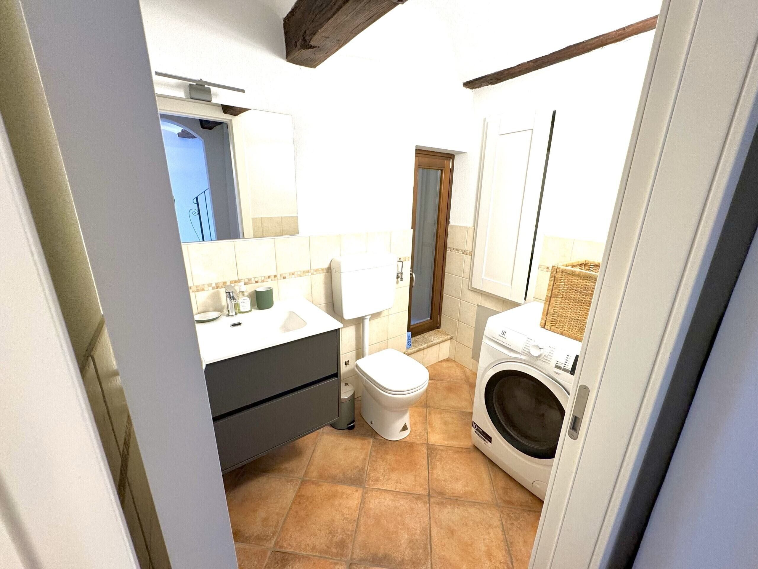 A compact bathroom with a sink, toilet, and washing machine.