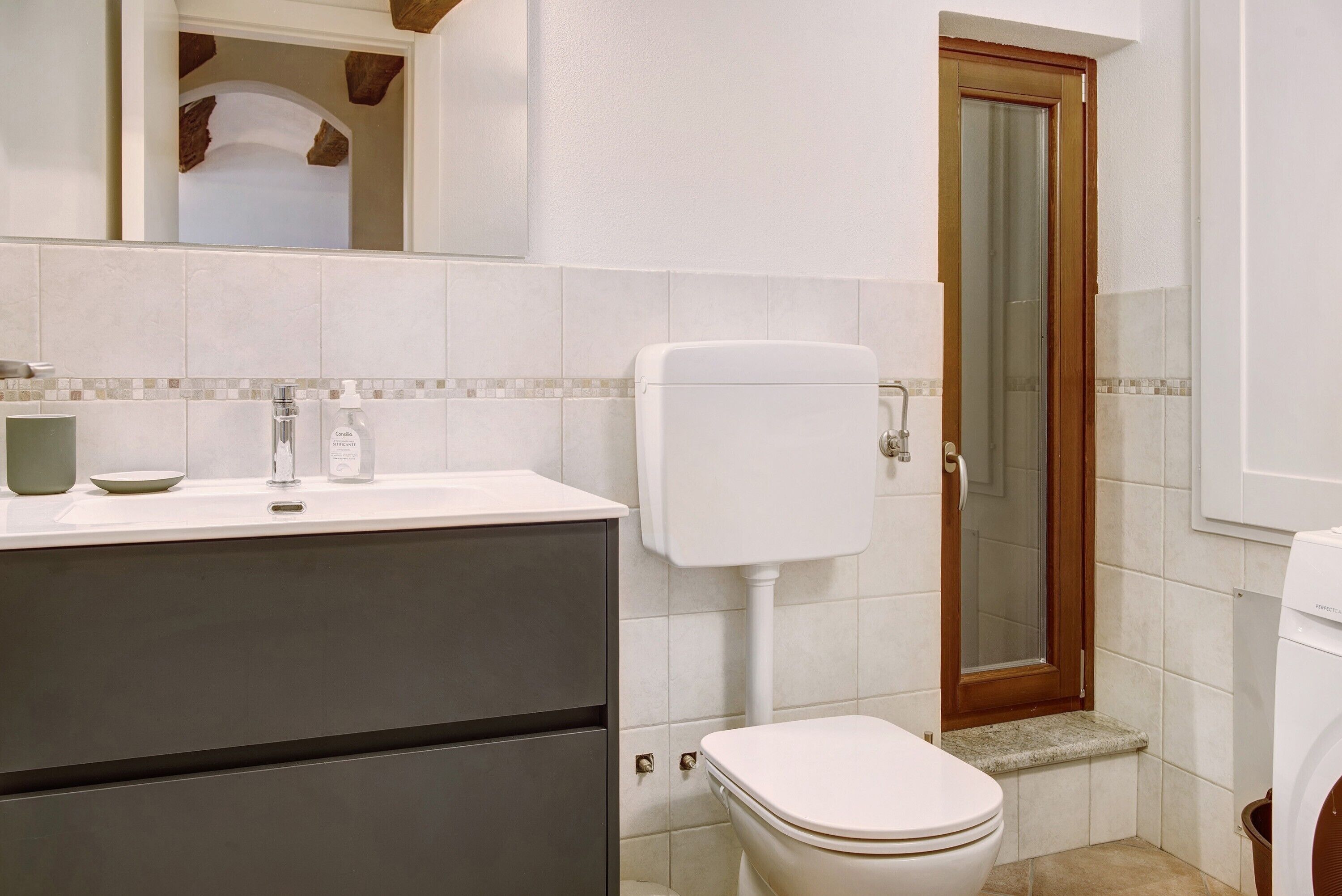 Un baño con inodoro, lavamanos y espejo.