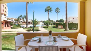 Tavolo imbandito per due con vista su piscina e palme.