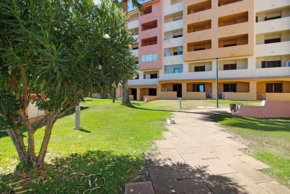 A multi-story building with balconies, a paved walkway, and a tree in the foreground. - Studio "Belavista House" with Private Terrace, Shared Pool & Wi-Fi (Albufeira)
