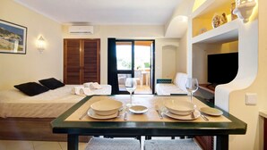 Camera d'albergo con un letto, un tavolo da pranzo apparecchiato con piatti e posate, una televisione e una finestra con vista.