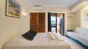 Una camera da letto con un letto, una divisa, una porta che dà su un'area esterna e un condizionatore d'aria a muro.