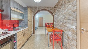 Une cuisine avec un évier rouge, des placards en bois et un coin repas comprenant une table et des chaises.