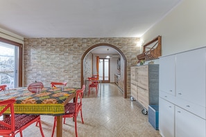 Un espace repas agrémenté d’un mur en briques, d’une arche en bois et d’un meuble avec des tiroirs.