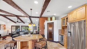 A kitchen with a large island, wooden cabinets, a stainless steel refrigerator, and a ceiling fan. - Luxury one level villa on 1/2 acre 12 min from The Strip (Las Vegas)