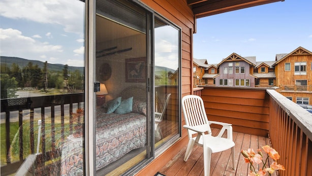 Varanda com cama, cadeira e vista para outros edifícios.