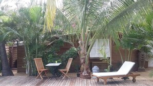 A wooden deck with a pool, two wooden chairs, a table, and a lounge chair. - Yuca-Spa  Studio de charme & spa-jacuzzi (Saint Paul)