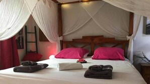 A bed with a canopy, pillows, and towels. - Yuca-Spa  Studio de charme & spa-jacuzzi (Saint Paul)