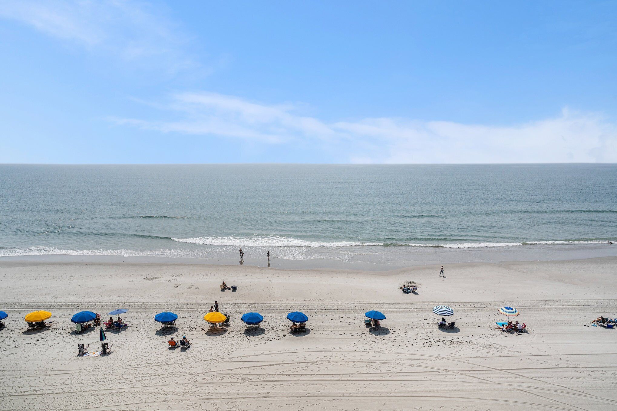 A beach with several umbrellas and people.