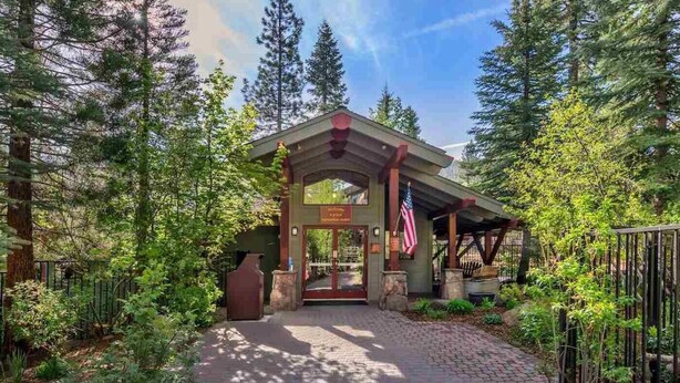 L'ingresso di un lodge con un portico coperto, una bandiera americana e un vialetto in mattoni che porta alla porta.