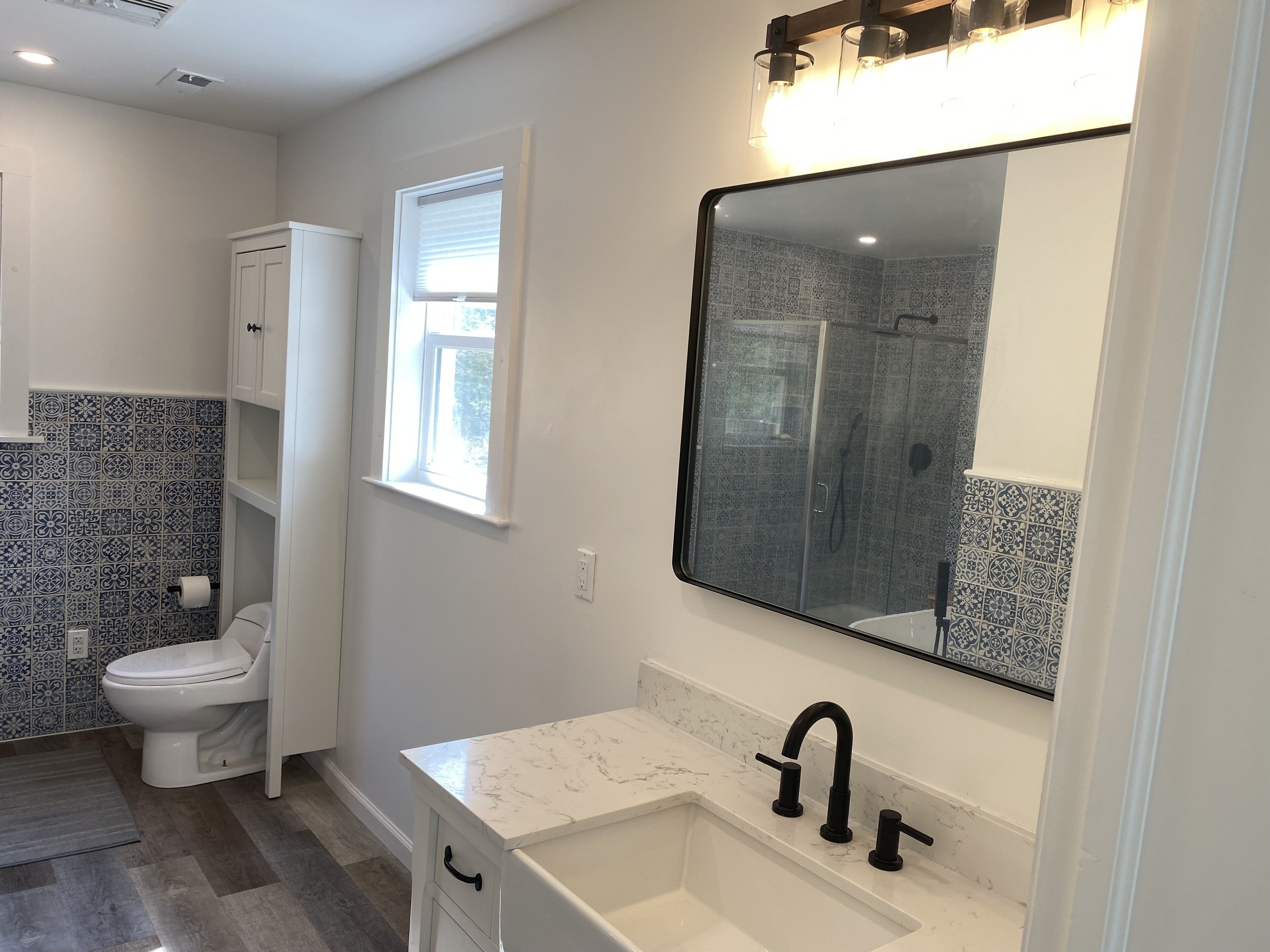 A bathroom with a toilet, a sink with a large mirror, and patterned tiles on the walls.