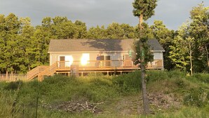 Uma casa de dois andares com varanda, cercada por vegetação densa e árvores.