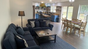 Uma sala de estar moderna com um sofá seccional, uma mesa de centro e uma área de jantar com cadeiras e mesa de madeira.