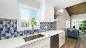 A modern kitchen with a large island, white cabinetry, and a blue-tiled backsplash.