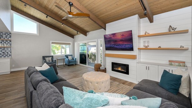 A spacious living room with a high ceiling, a fireplace, and a large TV mounted on the wall.