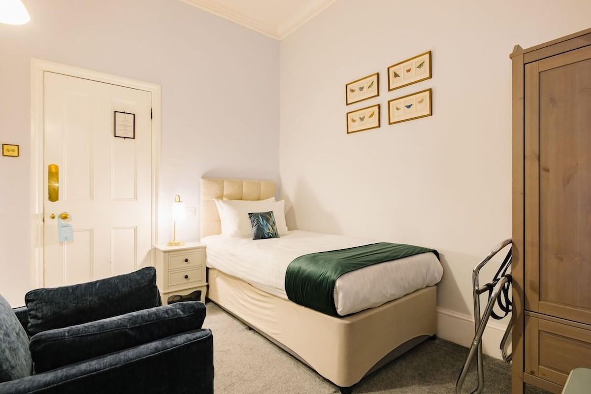 A bedroom with a bed, bedside table, lamp, and a wardrobe.