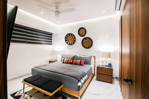 A modern bedroom with a bed, bedside tables, a bench, and decorative wall art.