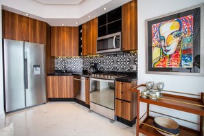A modern kitchen with wooden cabinets, a stainless steel refrigerator, a microwave, and a tiled backsplash. - NEW 1 BR w/pool and gym @ Desire (Puerto Vallarta)