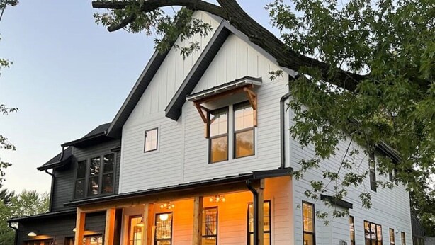 A two-story house with a covered porch and a well-maintained lawn. - New luxury home steps to downtown w/yr round heated pool (New Buffalo)