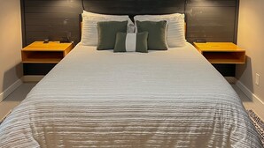 Un dormitori amb un llit gran, dues taules de nit, un ventilador de sostre i làmpades penjades a la paret.