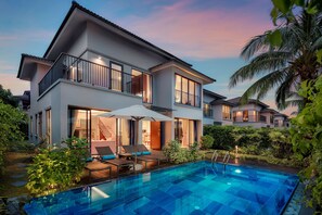 Una casa moderna de dos pisos con piscina, mobiliario exterior y un jardín bien cuidado.