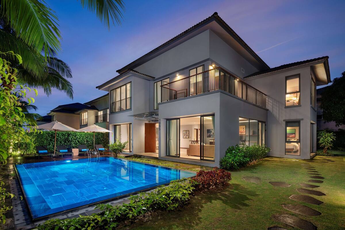 A modern two-story house with a swimming pool, large windows, and a well-maintained garden.