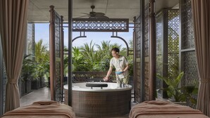 A spa room with a hot tub, two massage beds, and a person attending to the hot tub. - Best Western Premier Sonasea Villas Phu Quoc (Phu Quoc)
