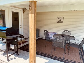 Eine Terrasse im Freien mit Grill, Metallstühlen und Tisch.