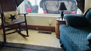 A room with a rocking chair, a bed, and a window with curtains.