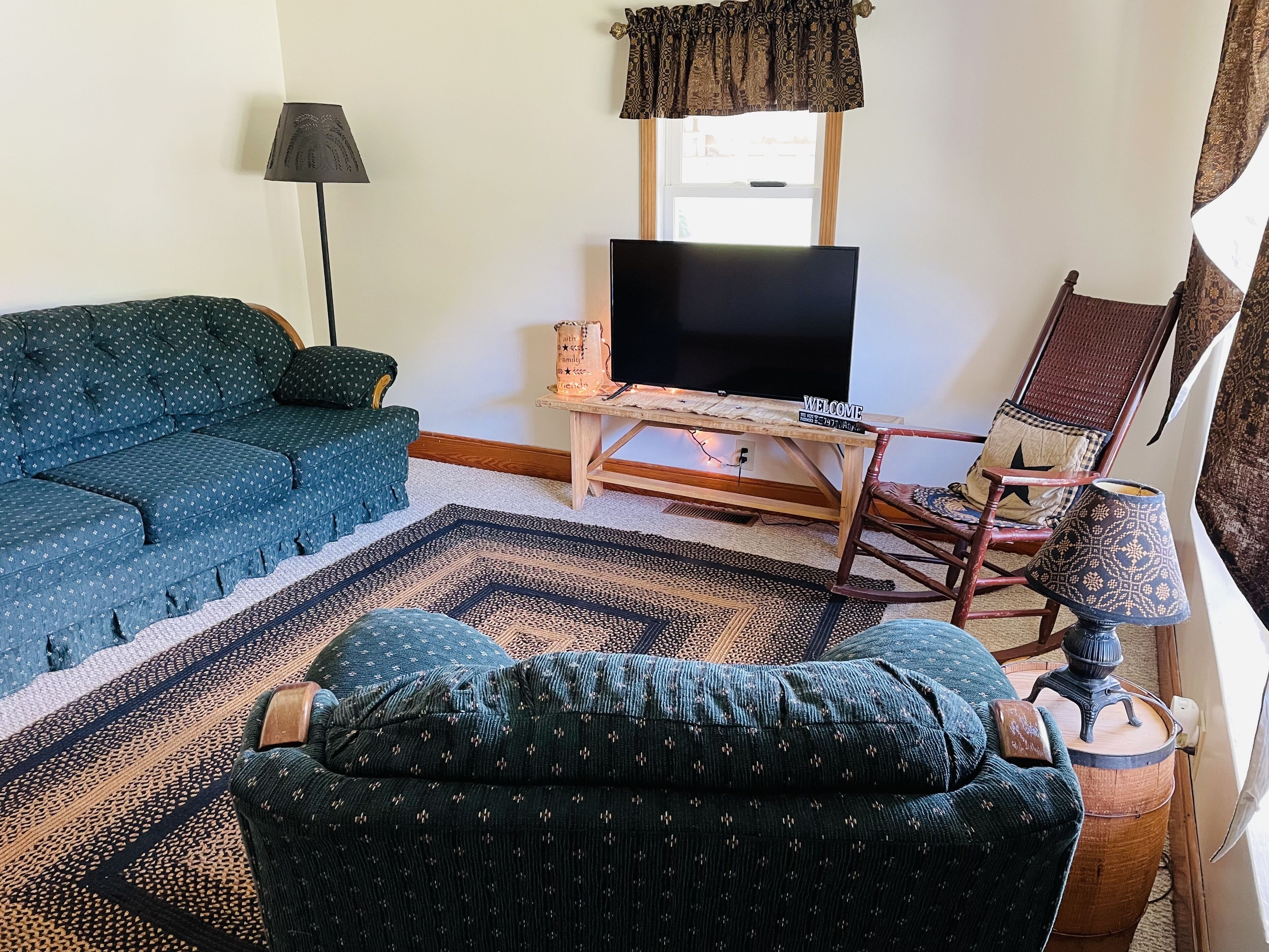 A living room with a sofa, a television on a wooden stand, a patterned rug, and a chair with a star pillow.