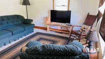 A living room with a sofa, a television on a wooden stand, a patterned rug, and a chair with a star pillow.